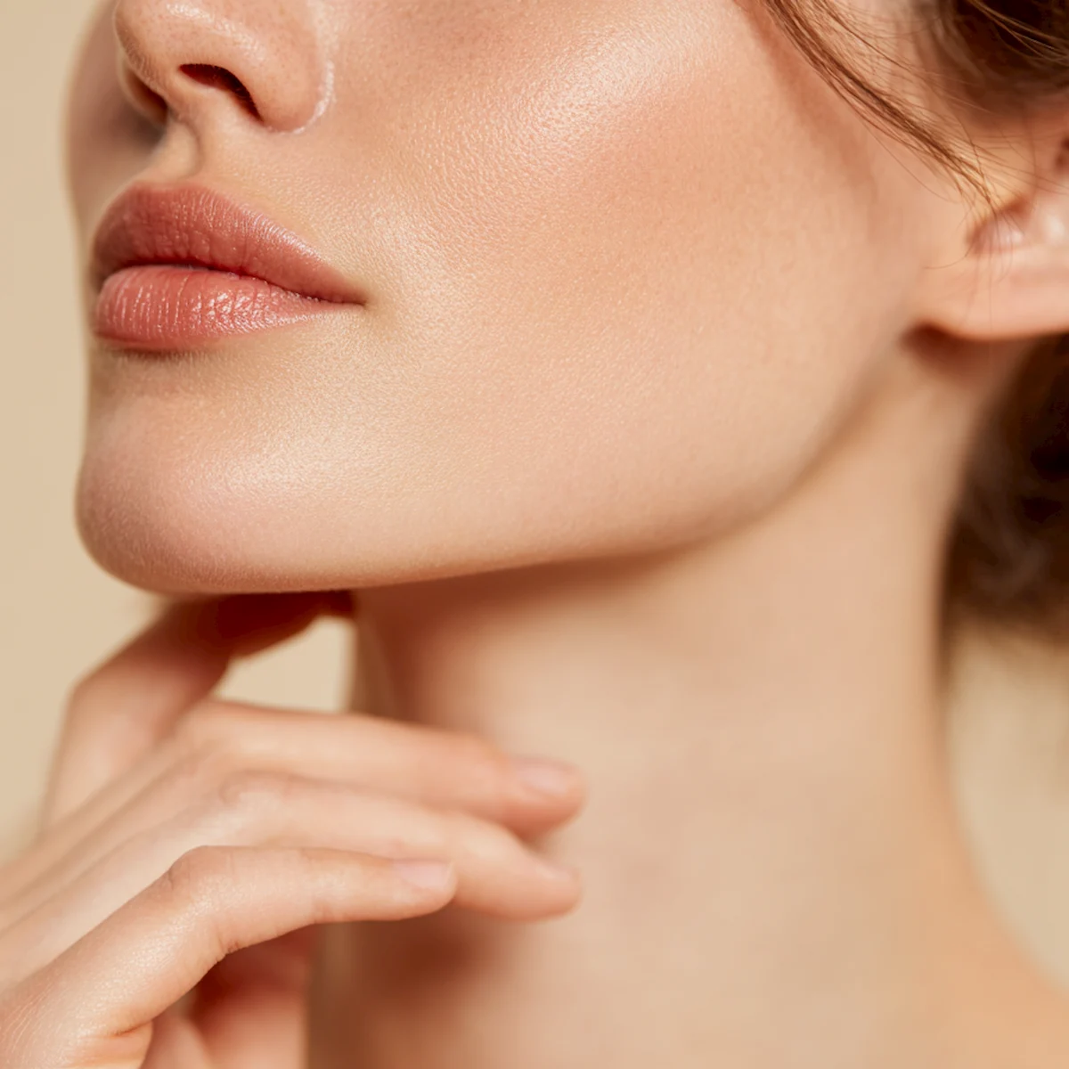 Woman with defined cheeks and jawline touching her chin, illustrating cheek filler treatment